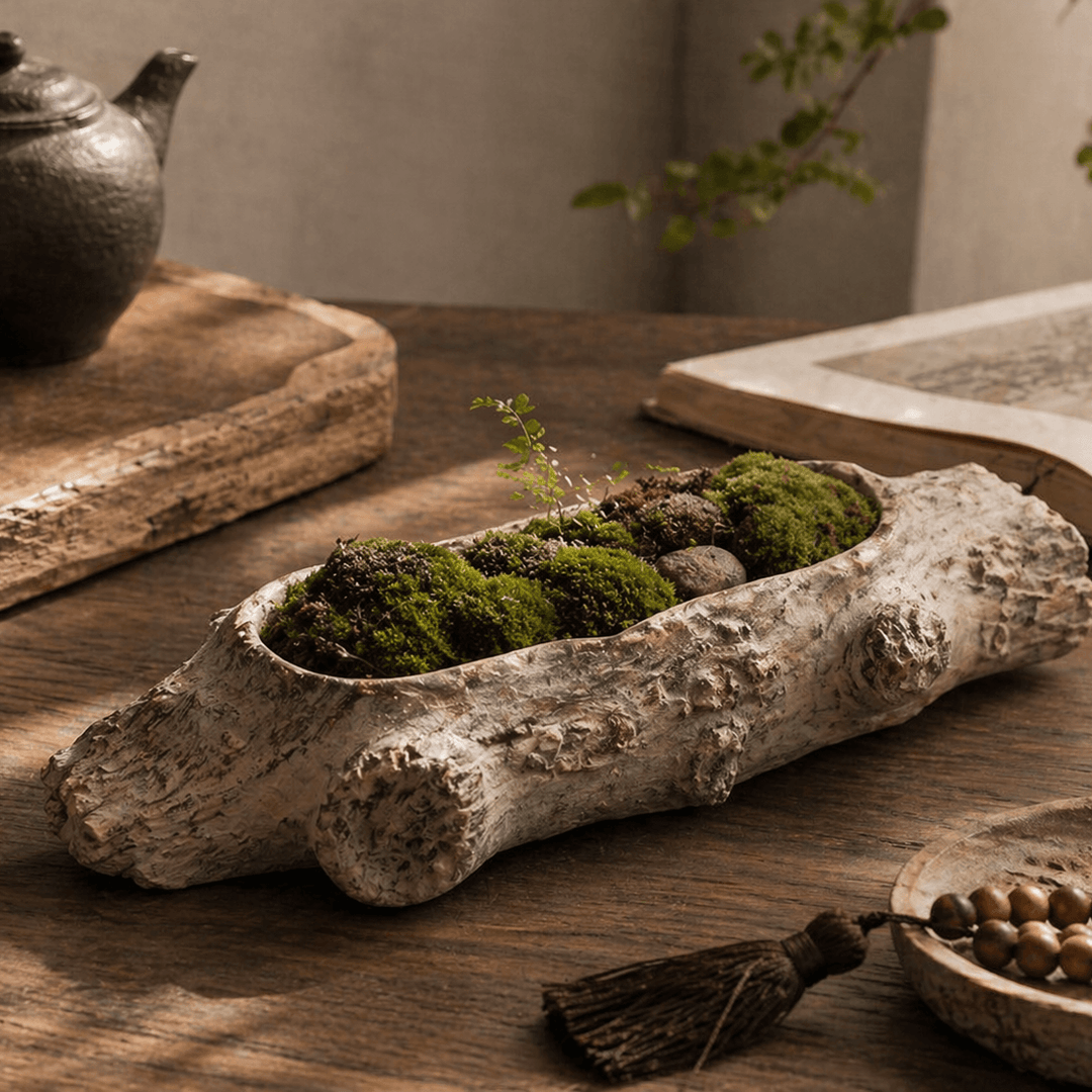 Pale cement log planter with moss on a wood table beside a book