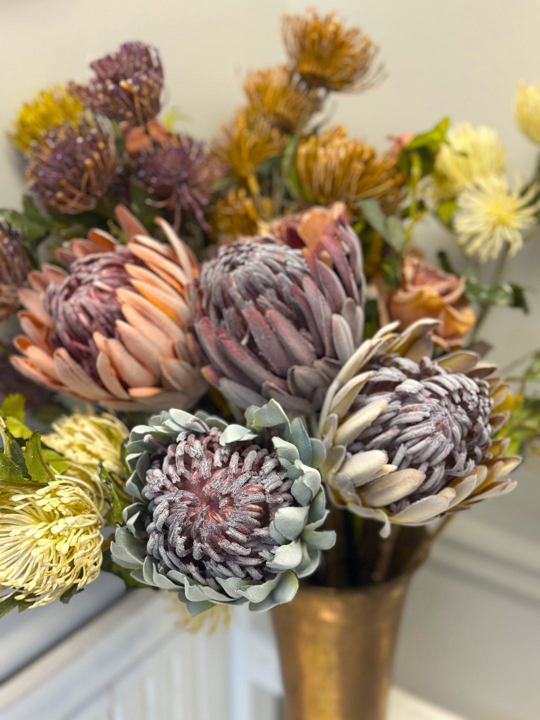 Close view of mixed king protea blooms in purple, pink, white, and blue tones