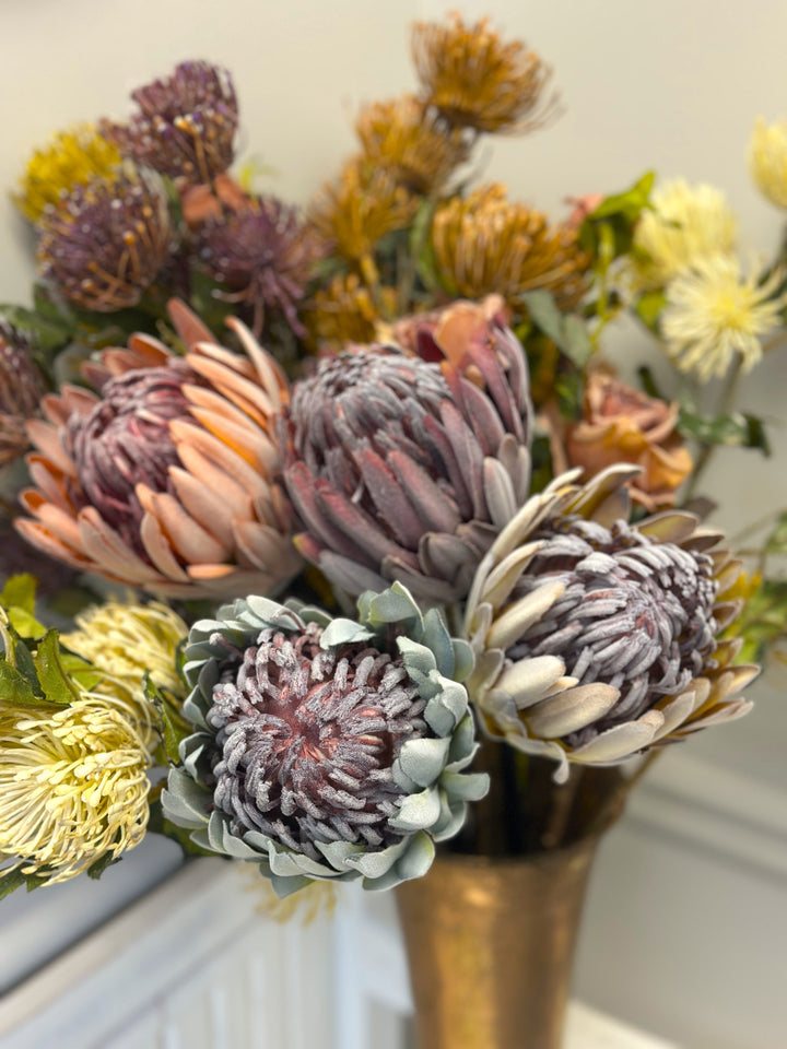 Close view of mixed king protea blooms in purple, pink, white, and blue tones