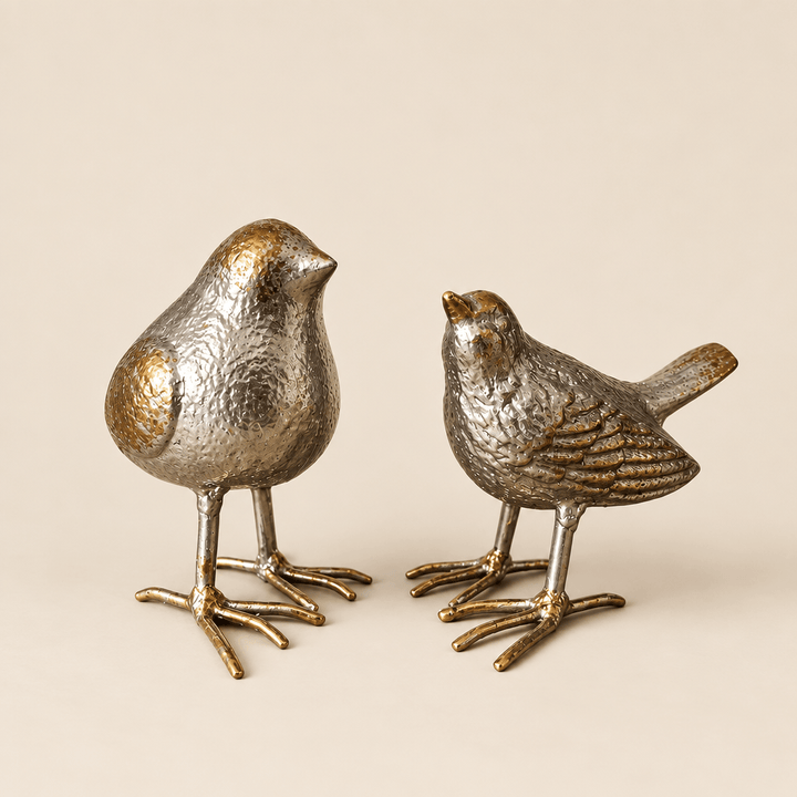 Silver-finish cast iron bird sculptures on a warm ivory studio background