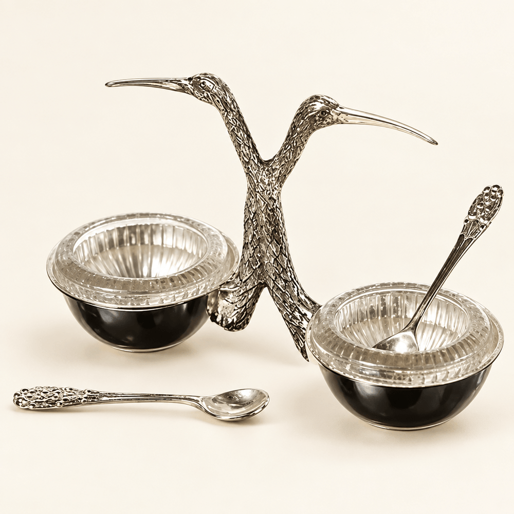 Stork salt and pepper cellar with glass inserts and silver spoons on an ivory studio background