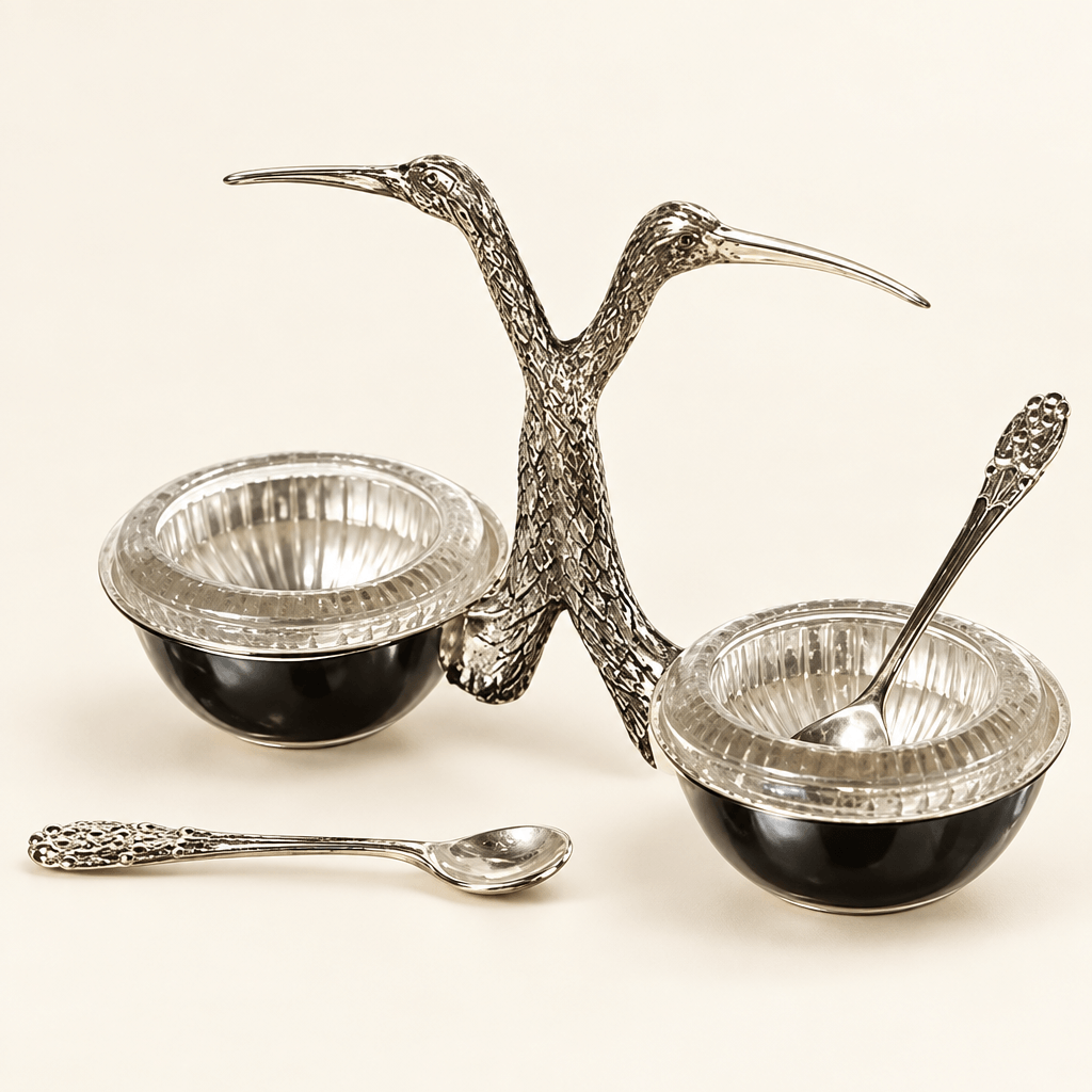 Stork salt and pepper cellar with glass inserts and silver spoons on an ivory studio background