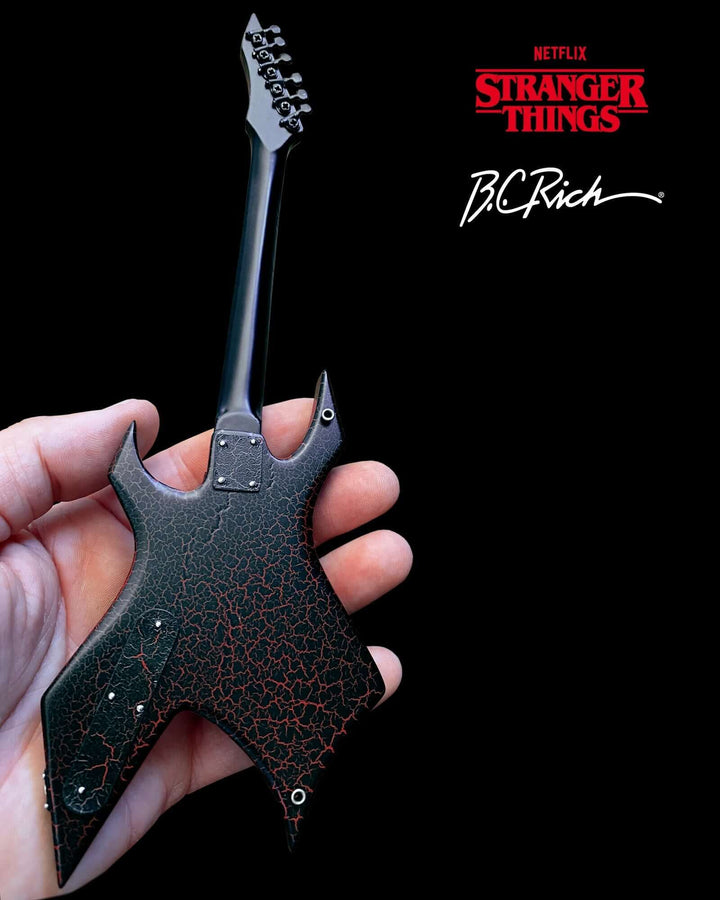 Hand holding Stranger Things Eddie’s B.C. Rich Warlock Mini Guitar Replica, showcasing the intricate craftsmanship.