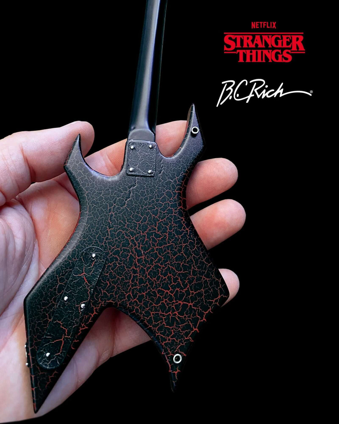 Hand holding Stranger Things Eddie’s B.C. Rich Warlock Mini Guitar Replica, showcasing its detailed craftsmanship and iconic design.