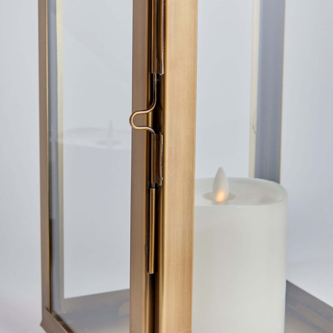 Close-up of tall antique brass candle lantern showcasing elegant metalwork and soft candle glow, evoking historic charm and nostalgia.