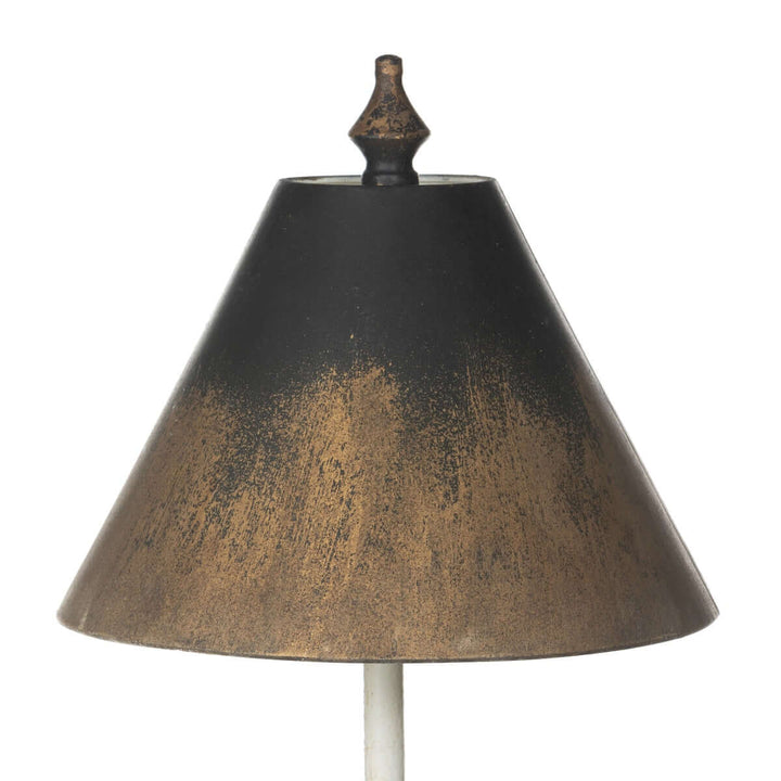 Close-up of black and gold shade on a tall vintage table lamp with distressed detailing, evoking a nostalgic, timeless charm.