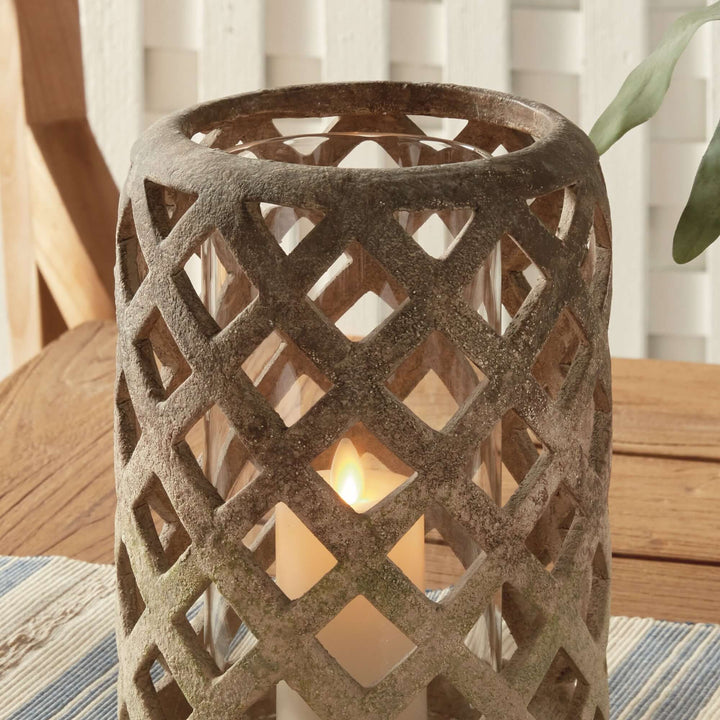 Terracotta hurricane candle holder with glass insert, featuring an airy lattice design and soft flickering candlelight.