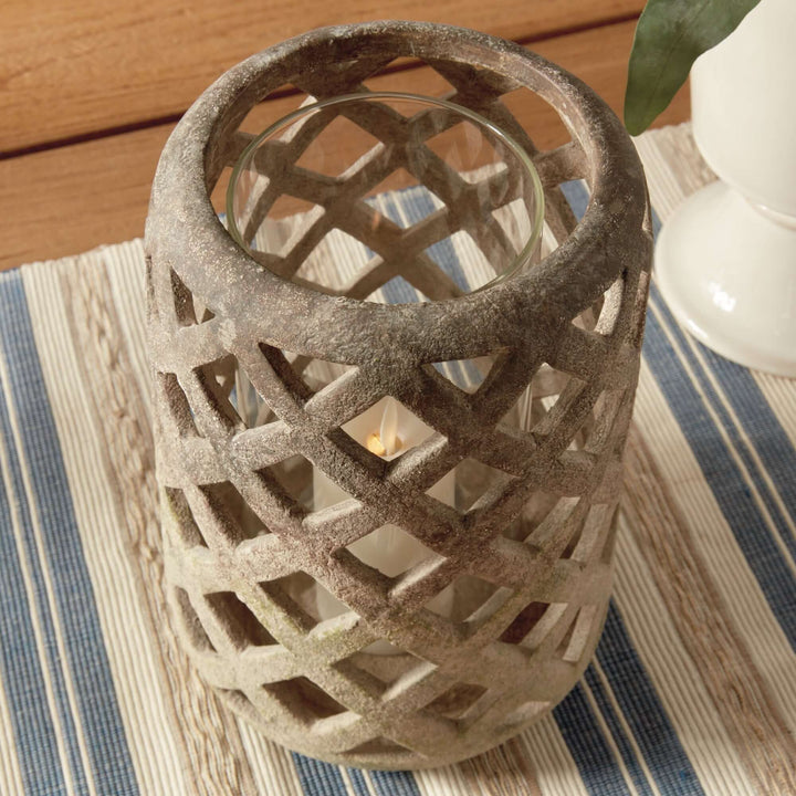 Terracotta hurricane candle holder with glass insert, featuring a lattice design and soft flickering light.