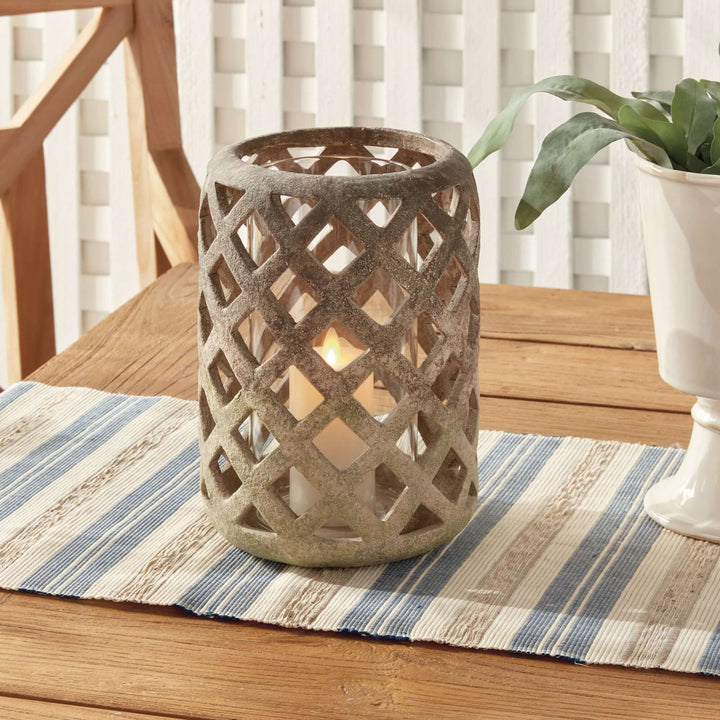 Terracotta hurricane candle holder with glass insert, featuring an airy lattice design and candle, perfect for home decor.