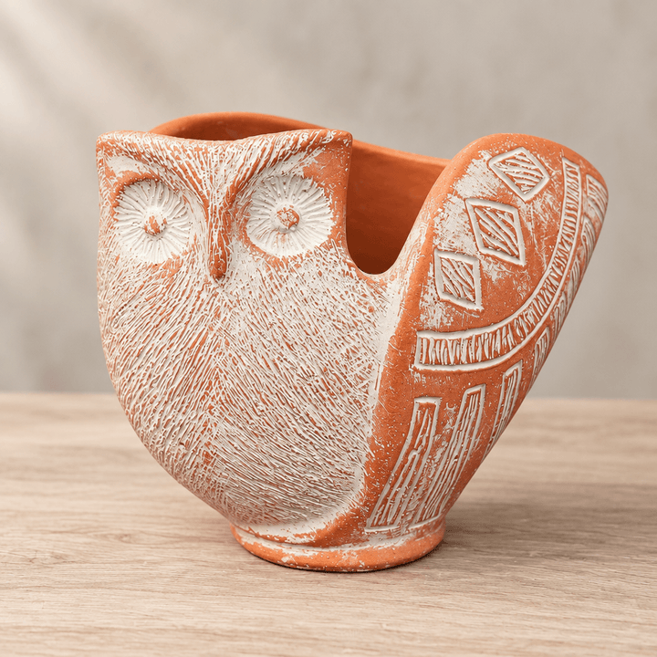 Close-up of round owl eyes, whitewashed feather texture, and geometric wing details on a cement planter