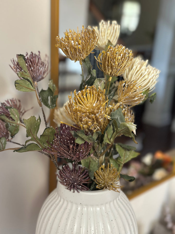 Yellow and purple pincushion protea faux stems styled in a white ceramic vase