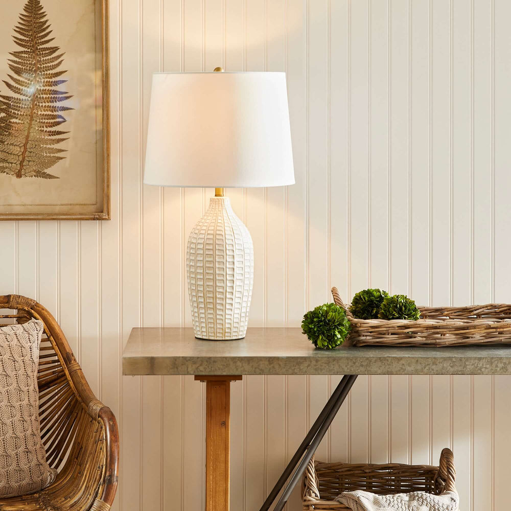 Textured vintage ceramic table lamp in white glaze on a rustic table, enhancing the home decor with warmth.