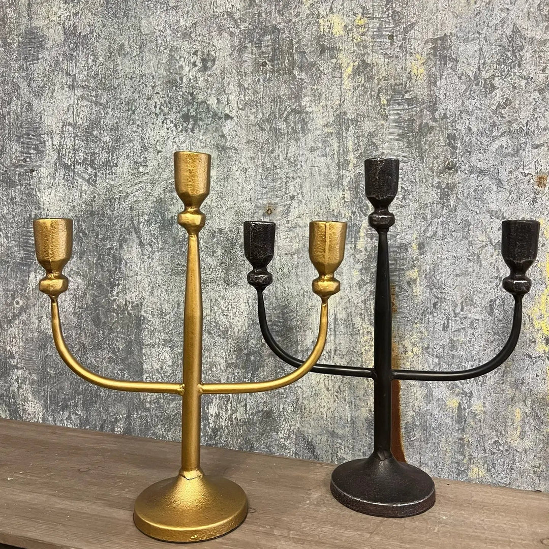Black and gold three-arm candelabras side by side