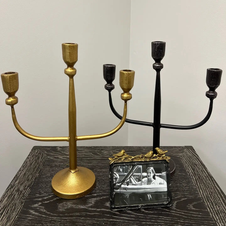 Gold and black candelabras arranged beside a framed photograph