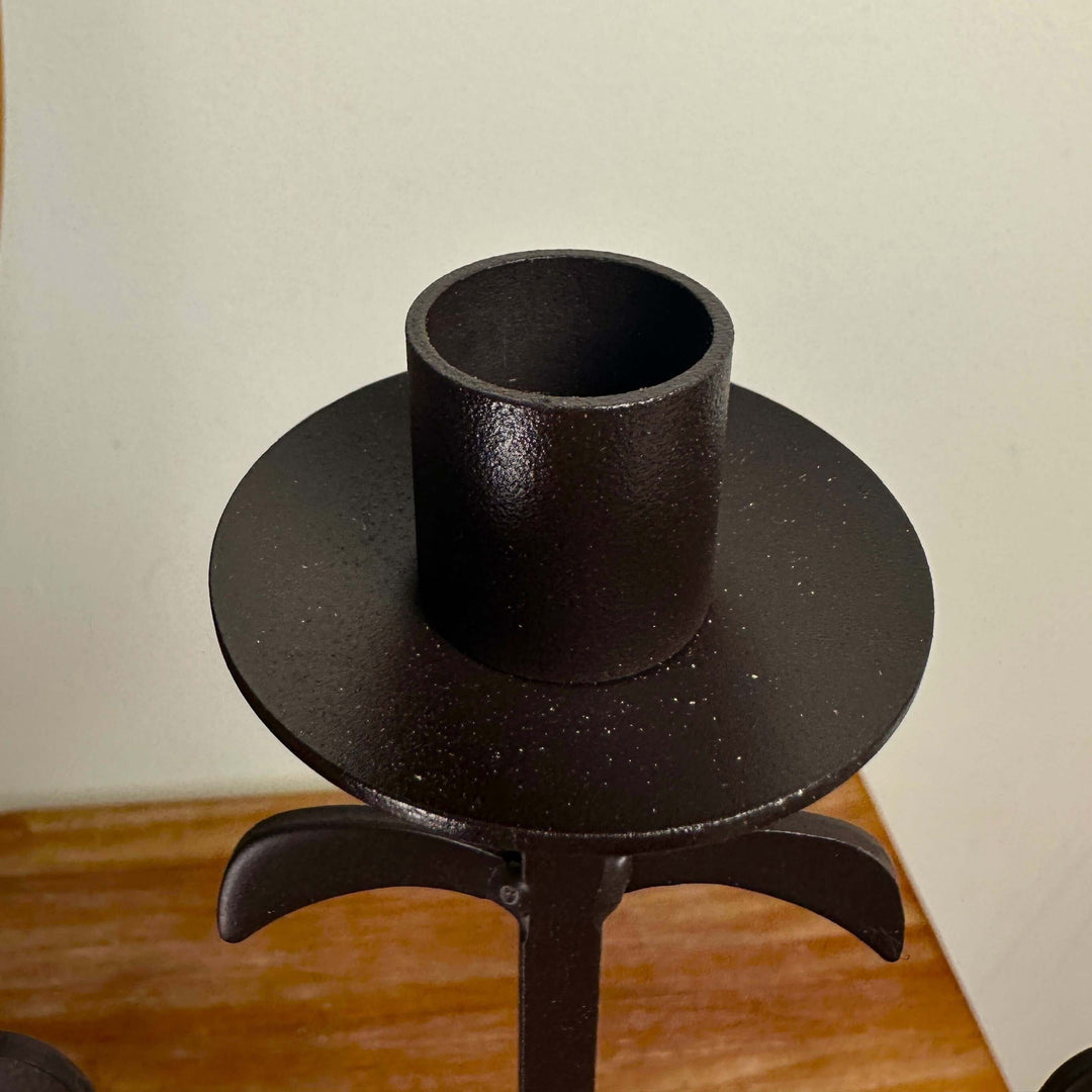 Candle cup and sculptural accent detail on rustic iron candelabra