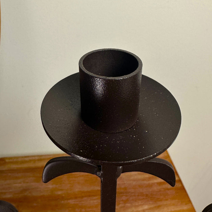 Candle cup and sculptural accent detail on rustic iron candelabra