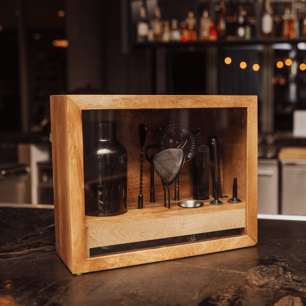 Vintage-Style Bartender Kit with Mango Wood Case & Bar Tools displayed on a bar counter, showcasing various cocktail tools in a stylish case.