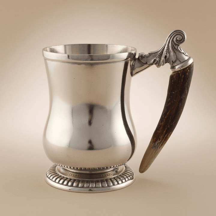 Silver mug with a horn handle on a beige background