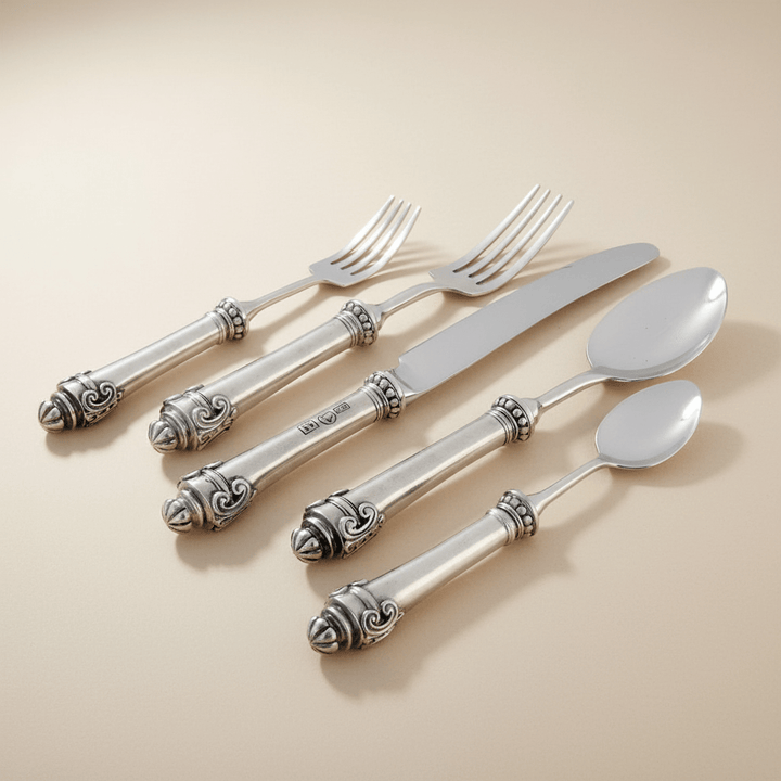 Set of silver cutlery with ornate handles on a beige background