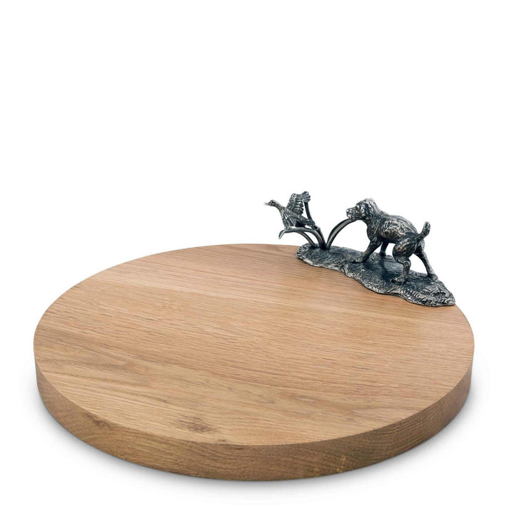 Wooden round cheese board with metal dog figurine on a white background