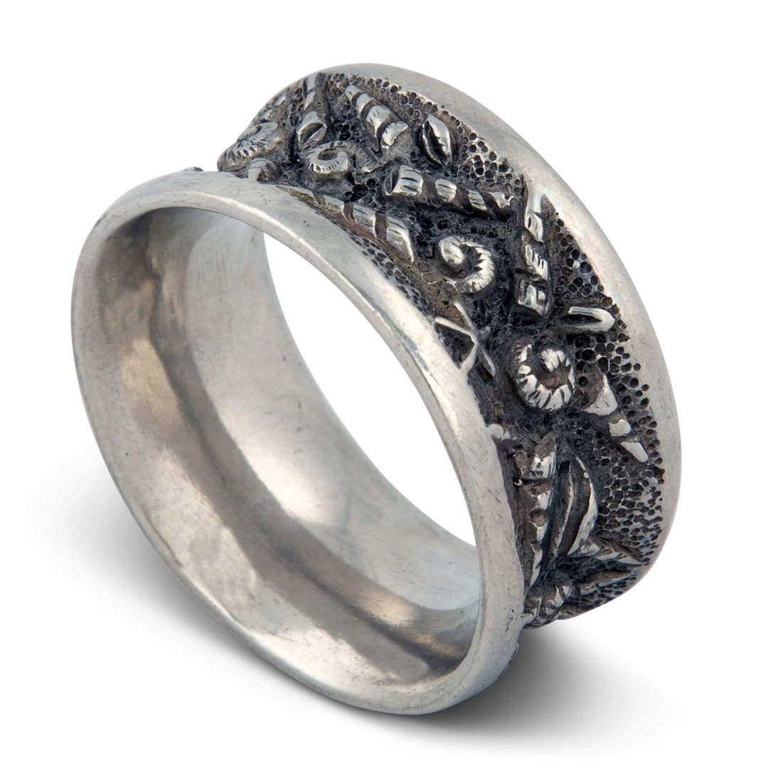 Silver napkin ring with intricate seashell design on a white background