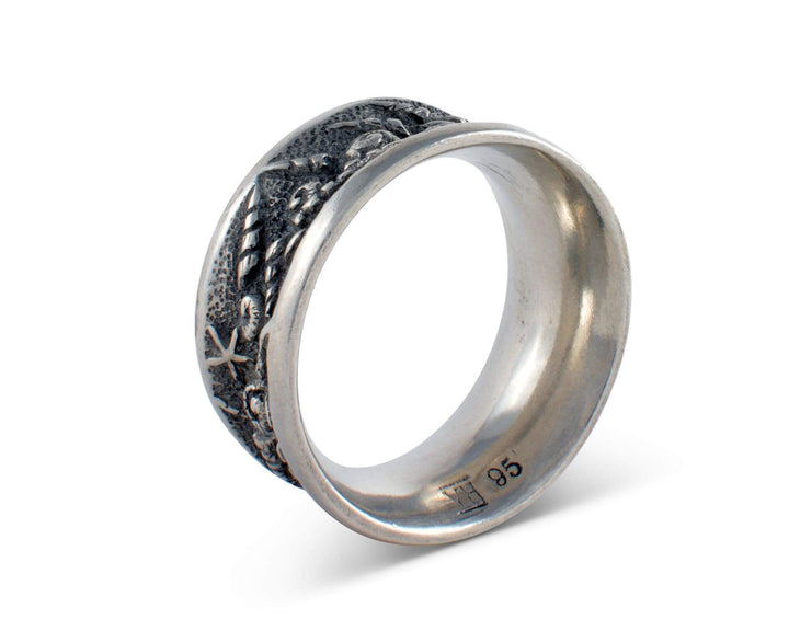 Silver napkin ring with intricate seashell design on a white background