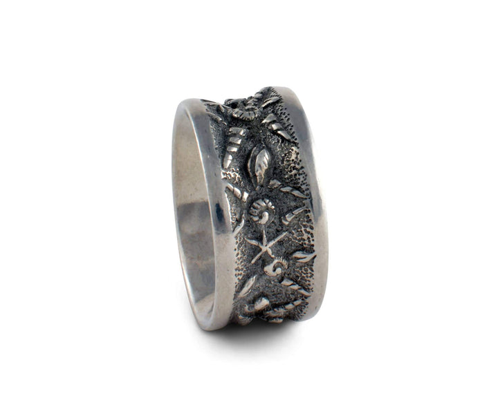 Silver napkin ring with intricate seashell designs on a white background