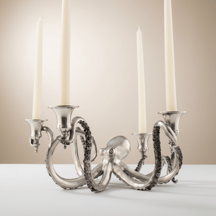 Silver octopus-shaped candle holder with four candles on a neutral background