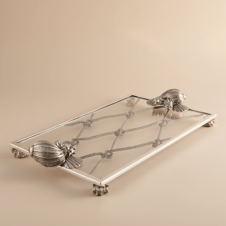 Decorative silver tray with shell designs on a beige background