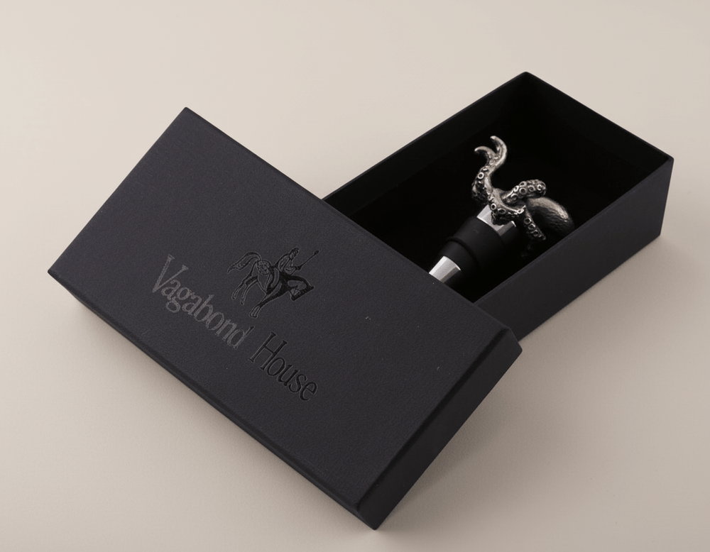 Black box with 'Vagabond House' branding containing a decorative bottle stopper.