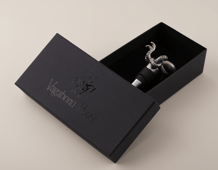 Black box with 'Vagabond House' branding containing a decorative bottle stopper.