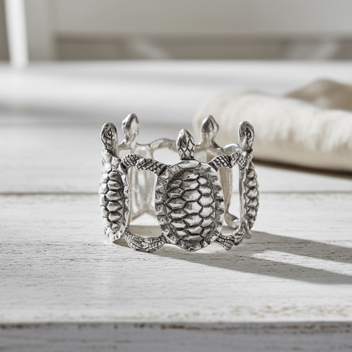Silver napkin ring with intricate turtle design on a wooden surface