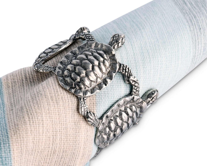 Metallic turtle-shaped napkin ring on a folded fabric background