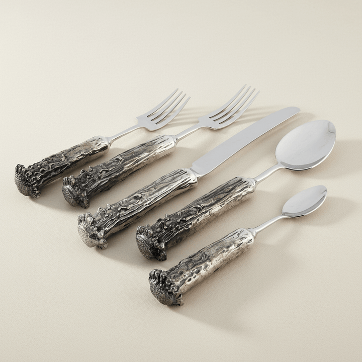 Set of pewter flatware with Western styled antler handles on a beige background