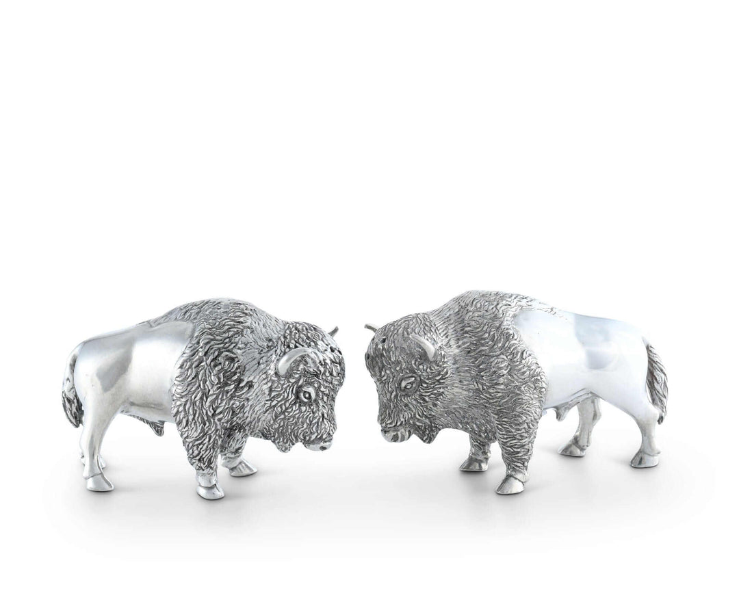 Two silver buffalo figurines facing each other on a white background