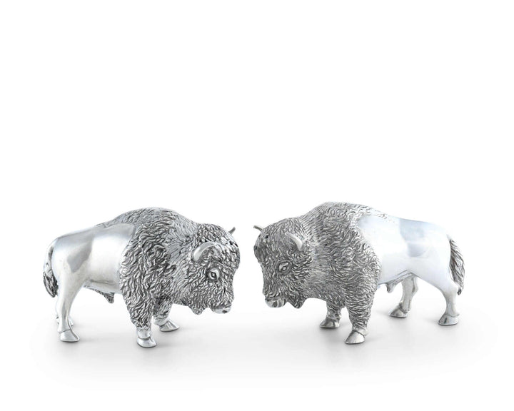 Two silver buffalo figurines facing each other on a white background