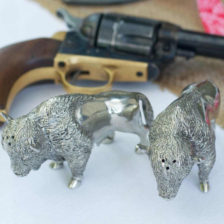 Silver buffalo salt and pepper shakers with a revolver in the background