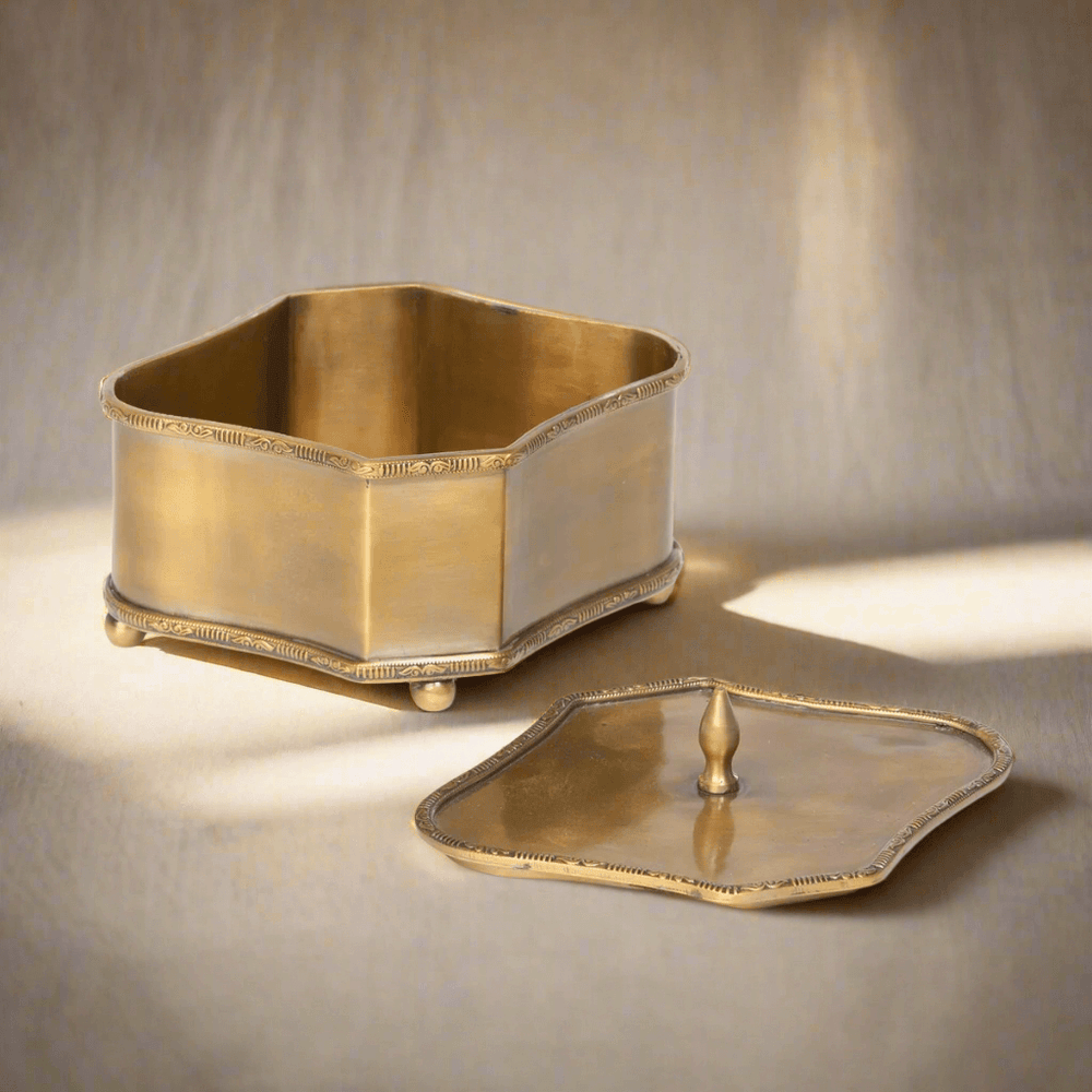 Vintage brass trinket box with lid showcasing decorative edging and ball feet, evoking old-world elegance.