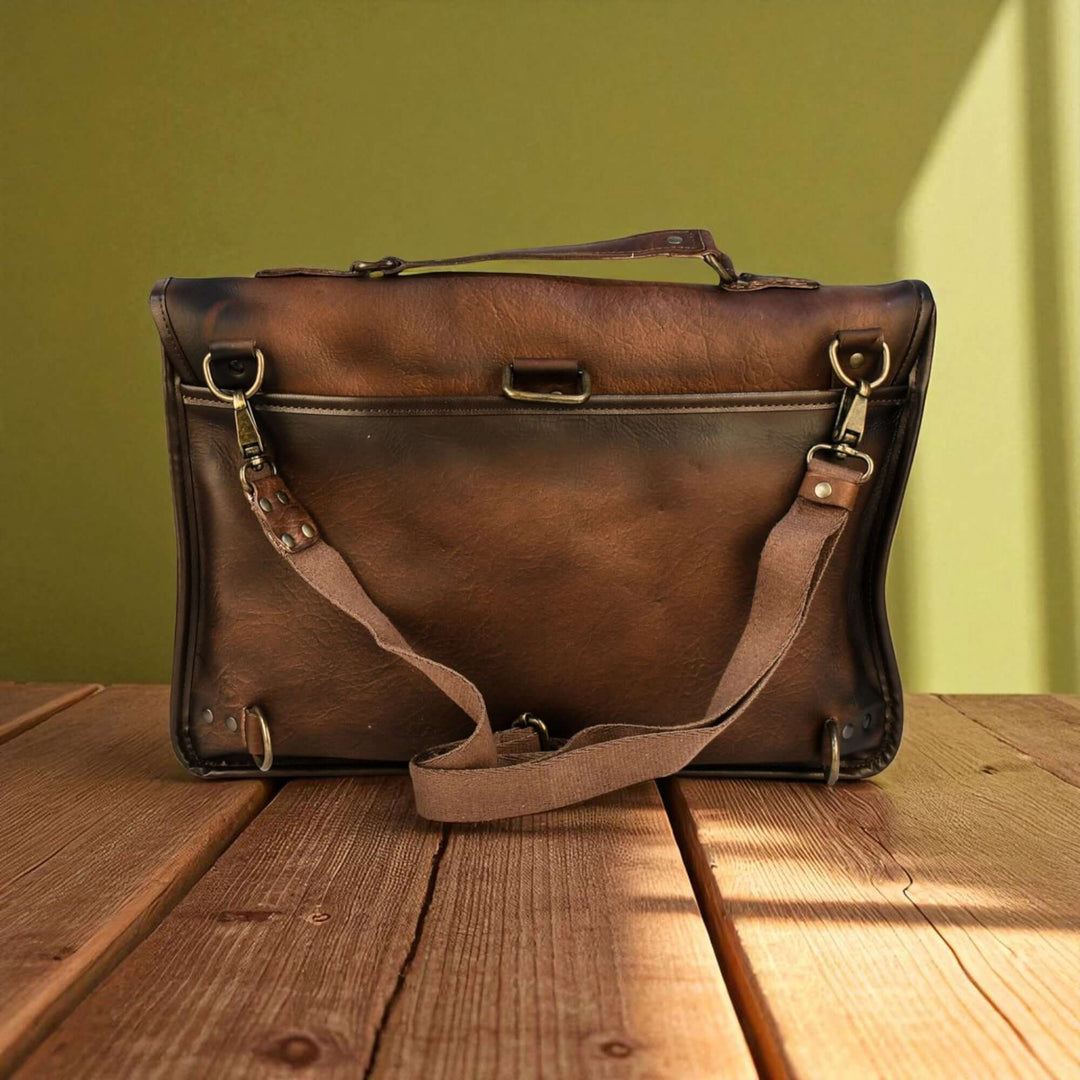 Vintage Brown Leather Laptop Bag with Twin Straps on wooden table in sunlight