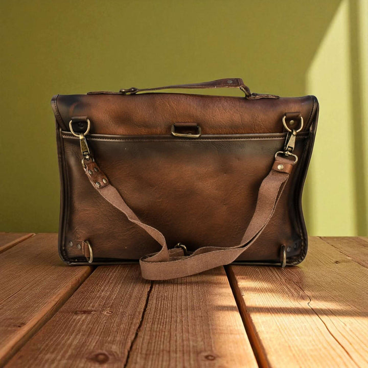 Vintage Brown Leather Laptop Bag with Twin Straps on wooden table in sunlight