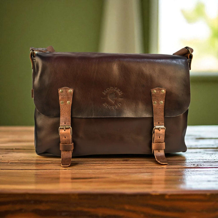 Vintage Brown Leather Messenger Bag on wooden table, showcasing rich oiled leather and buckled straps, perfect for timeless journeys.