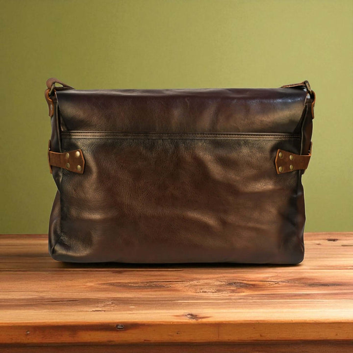 Vintage Brown Leather Messenger Bag on wooden table, classic design and timeless craftsmanship, perfect for travel and everyday use.