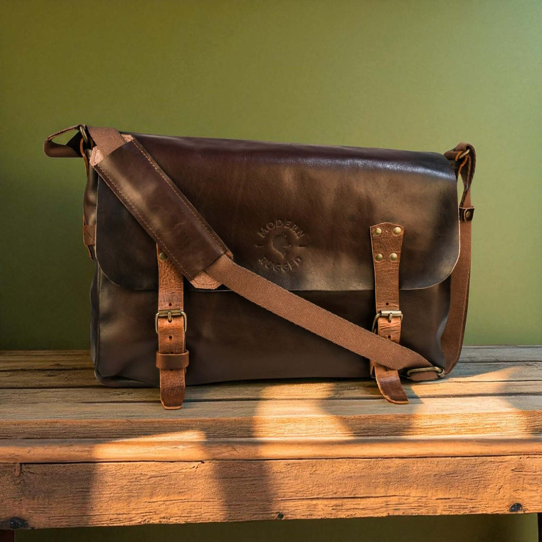 Vintage Brown Leather Messenger Bag with buckled straps on wooden table, timeless craftsmanship style