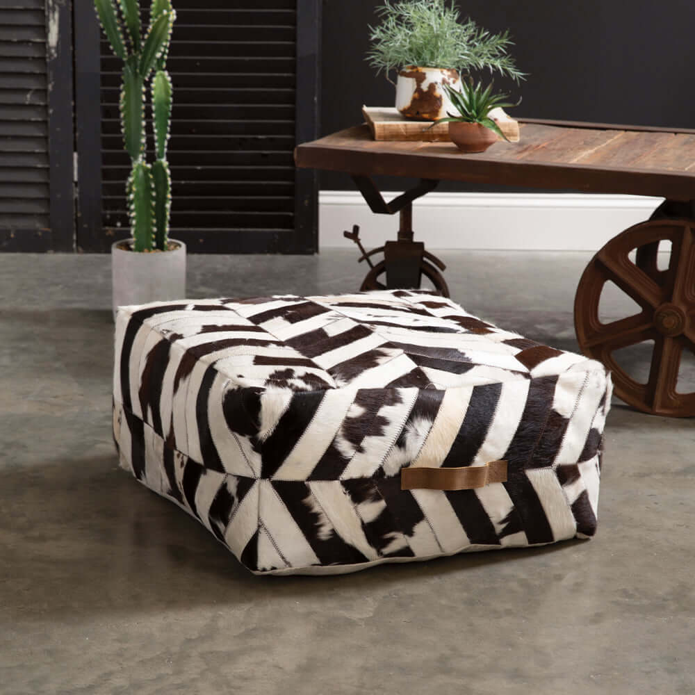 Vintage cowhide patchwork ottoman pouf in chevron pattern, showcasing rustic charm and bold Western flair.