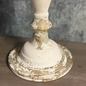 Base of Vintage Farmhouse Candelabra in Distressed White Iron displaying detailed weathered finish on rustic wooden surface.