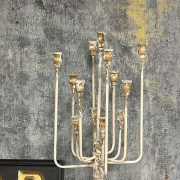 Vintage Farmhouse Candelabra in Distressed White Iron with rustic charm against a textured wall.