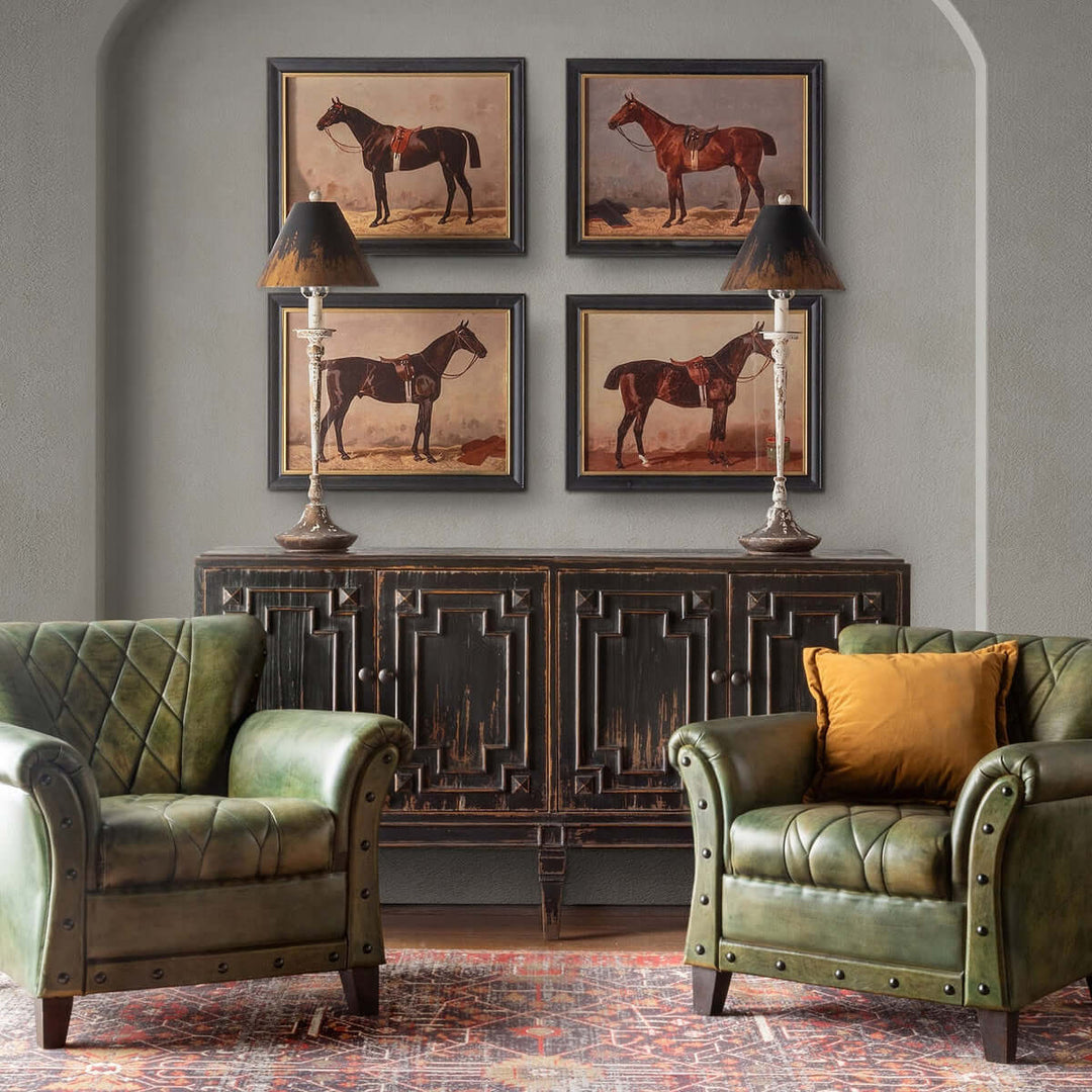 Cozy rustic living room with distressed buffet, antique farmhouse lamps, green armchairs, and vintage horse artwork.