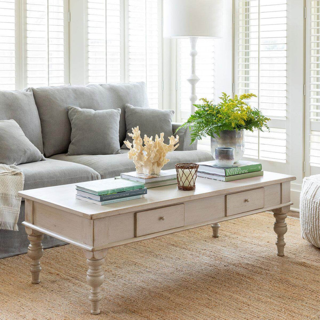 Vintage French Country Whitewashed Coffee Table With Drawers in a cozy living room setting, grey sofa, decorative accents.