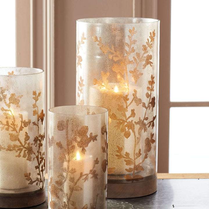Vintage glass hurricane candle holders with botanical etching, showcasing warm candlelight and elegant floral motifs.