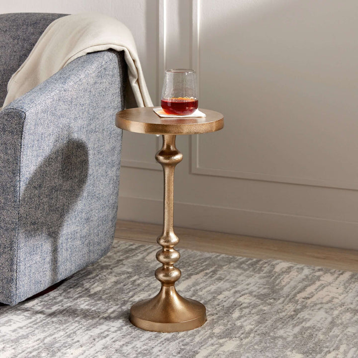 Vintage gold accent table with pedestal base, perfect for adding charm to a sitting nook or reading corner.